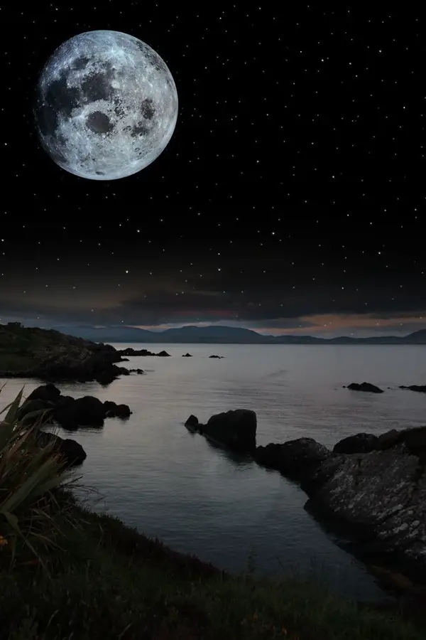 night scenic view in kerry ireland of rocks and sea with mountains against a beautiful blue cloudy sky