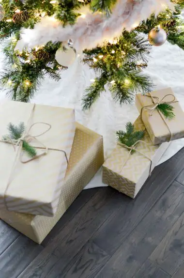 A Christmas tree with ornaments and lights and gifts boxes placed below