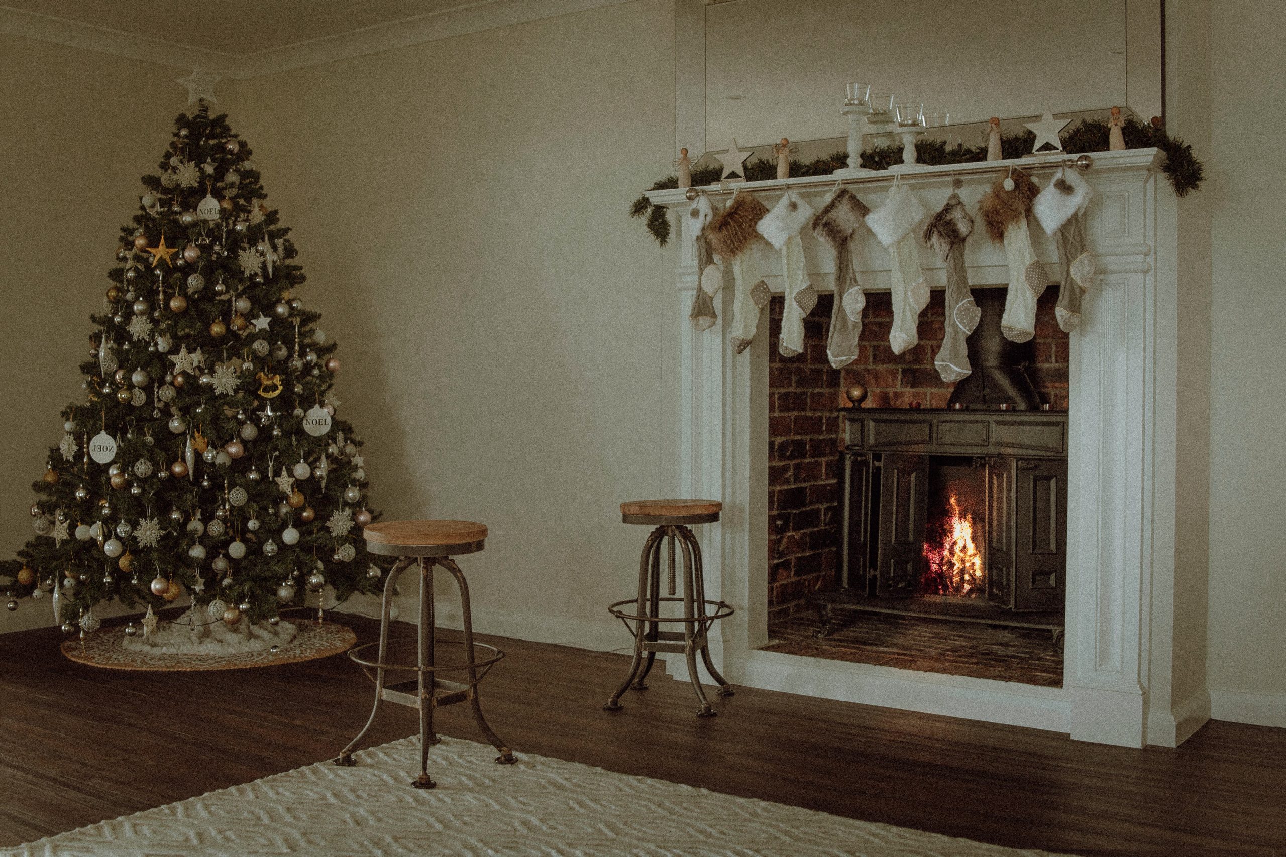 A Christmas tree featuring white decorative elements in a white room with a fireplace.
