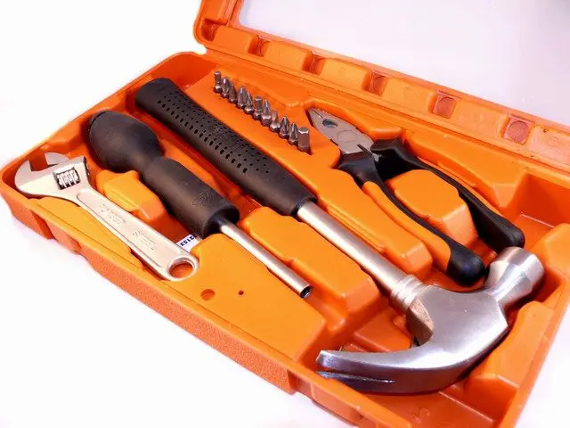 Four tools placed in a toolkit An orange-colored toolkit with different daily-use tools
