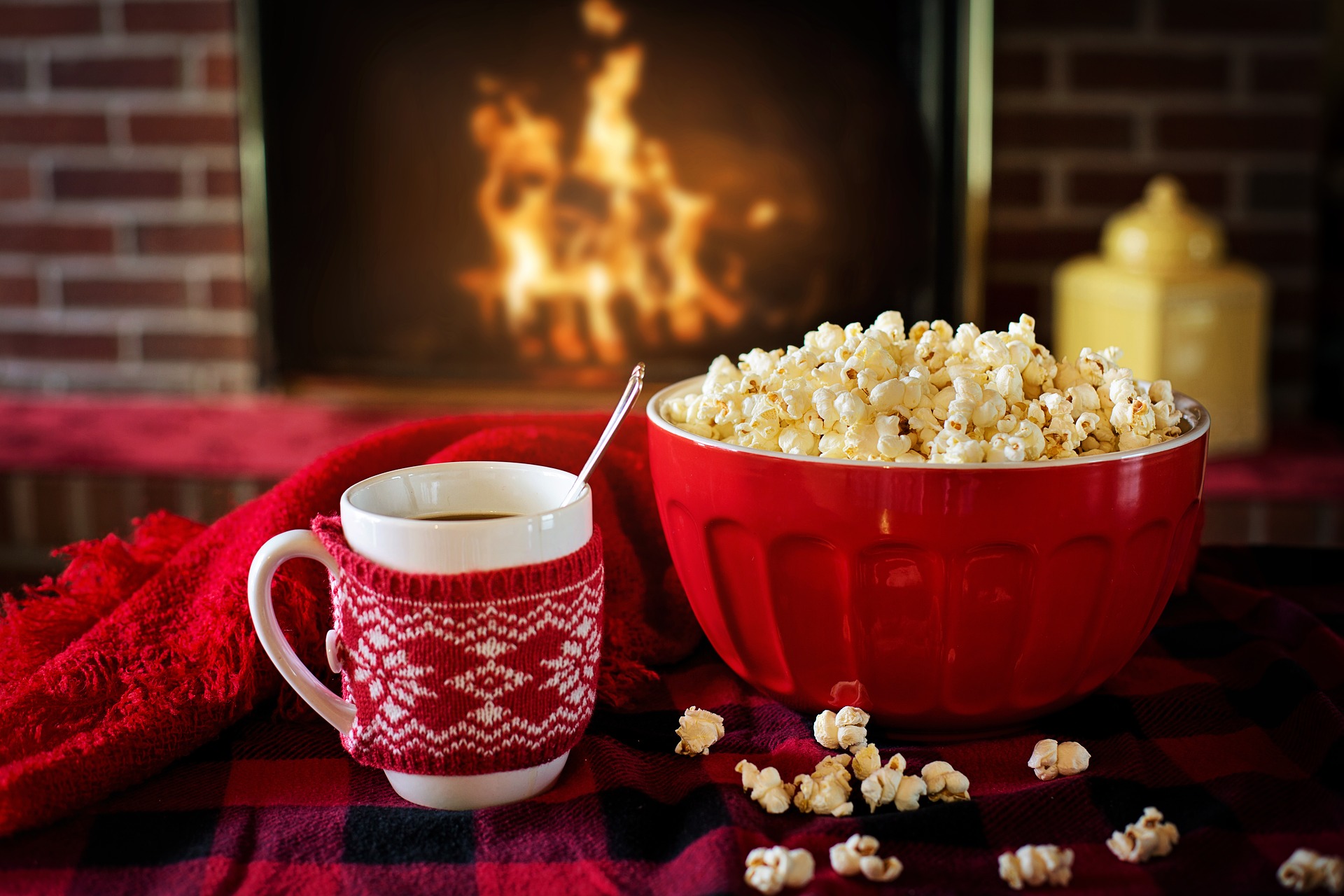 A mug of hot chocolate with a bowl of popcorn by the fireplace