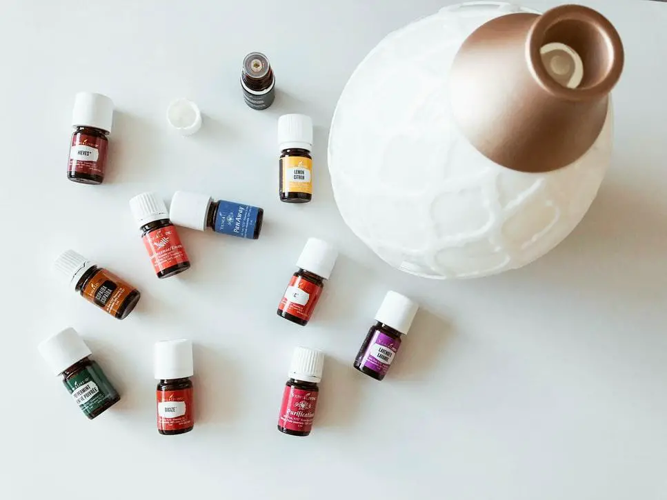 Multiple bottles of fragrant and essential oils placed on a surface along with an oil diffuser.