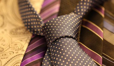 A black shirt tie with yellow polka dots, placed on top of other ties