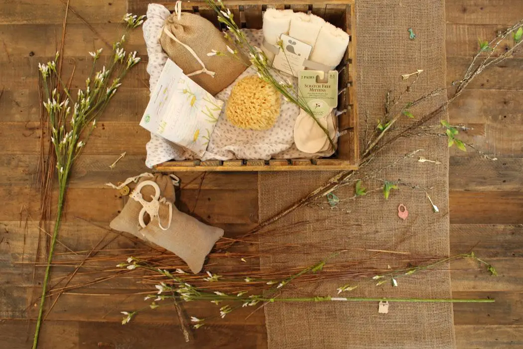 A spa gift box along with some weeds kept in a wooden basket on a wooden surface.