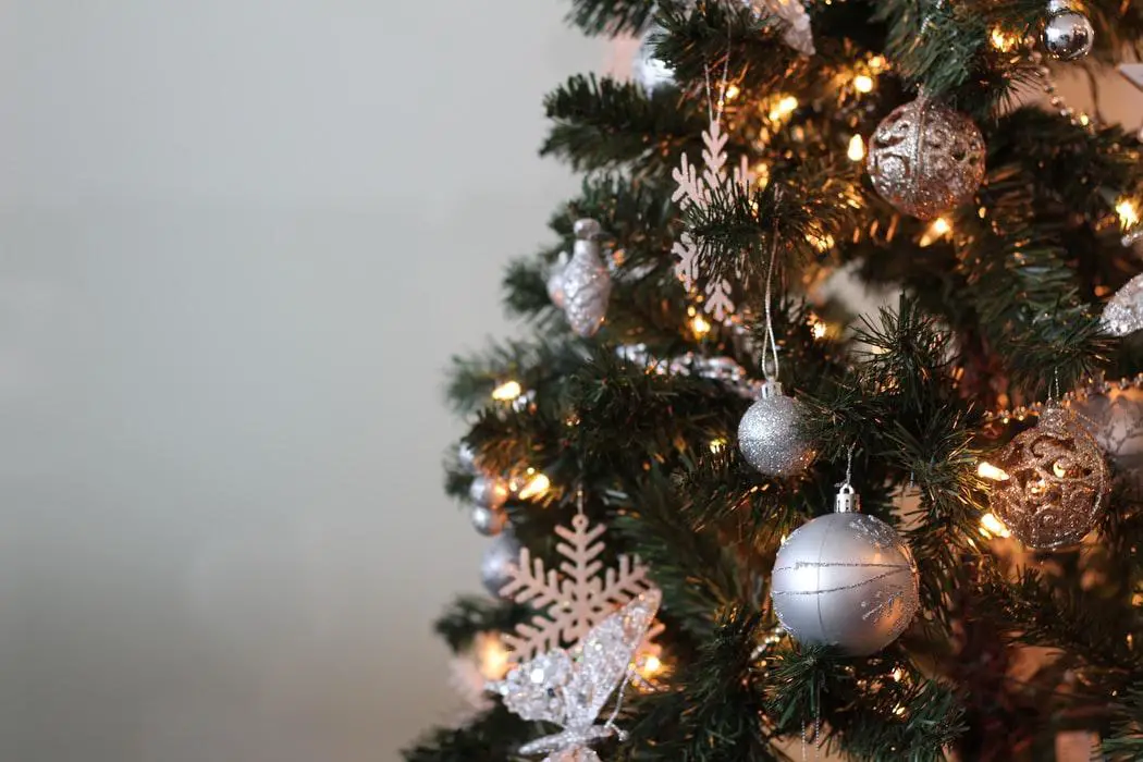 White baubles and snowflakes hanging from a Christmas tree.