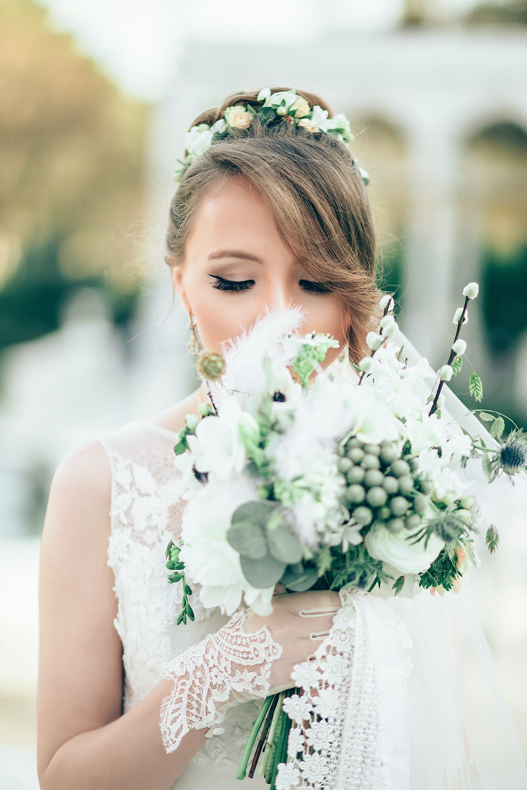 A bride dressed in white posing for a photograph with a bunch of flowers