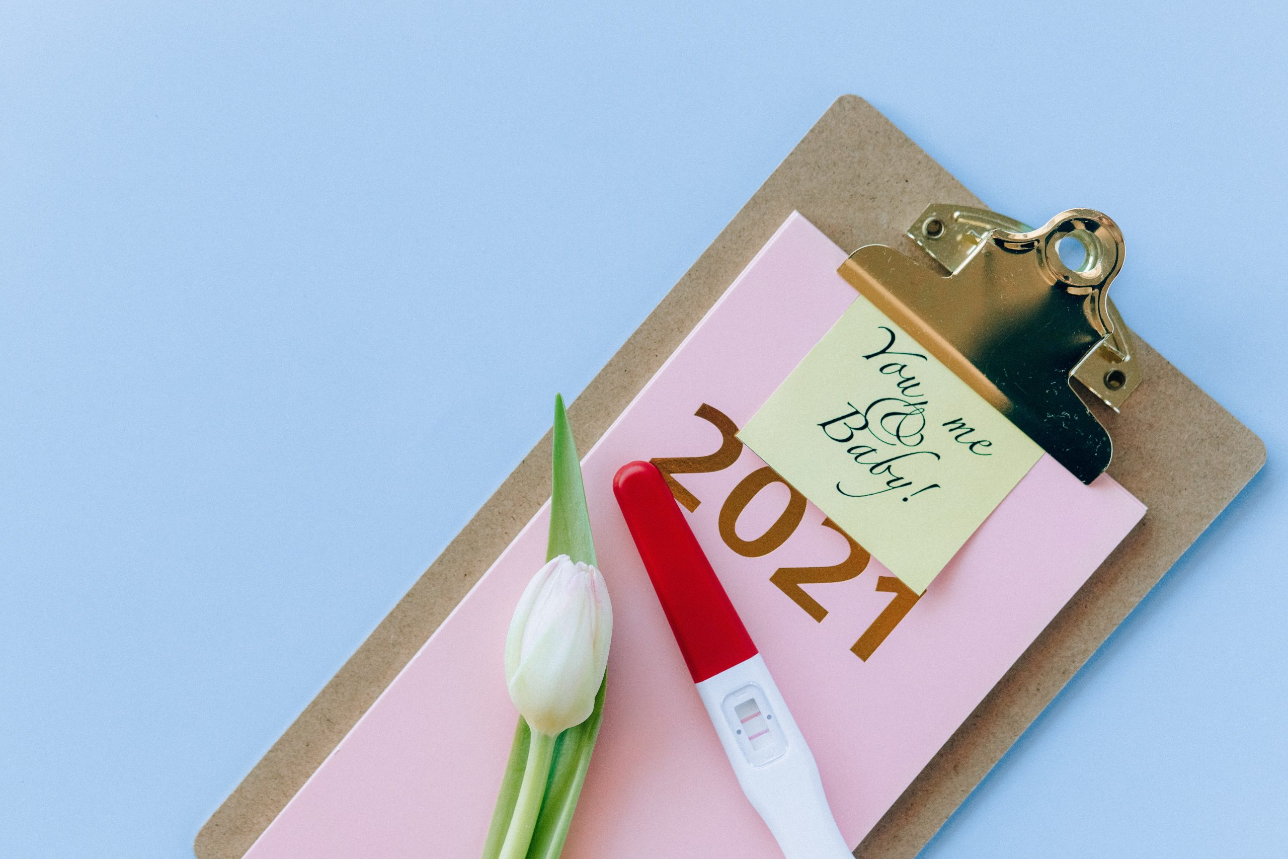 A pink notepad with a sticky note on top attached to a clipboard