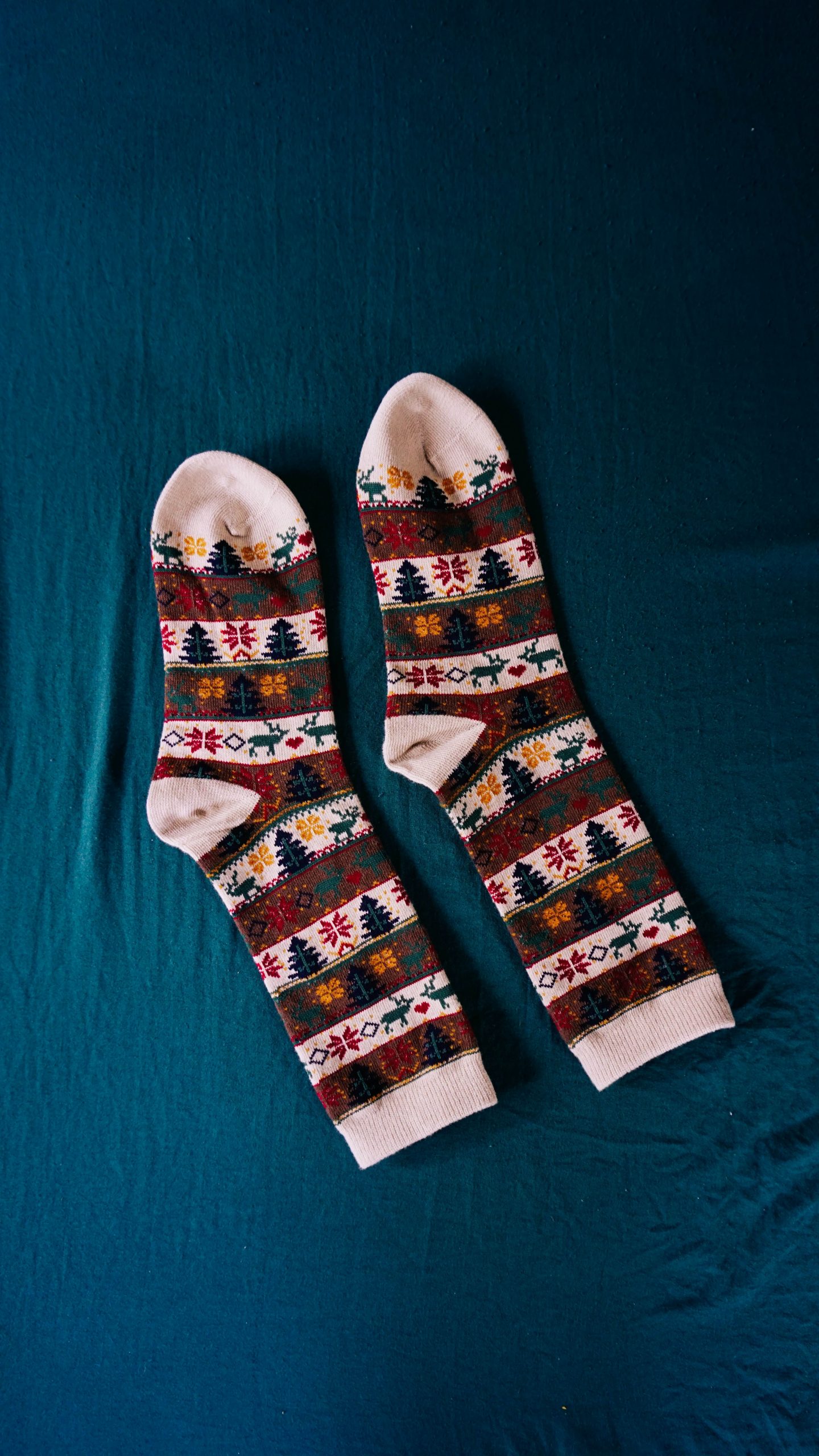 A pair of Christmas socks with imprinted Christmas trees and reindeer.