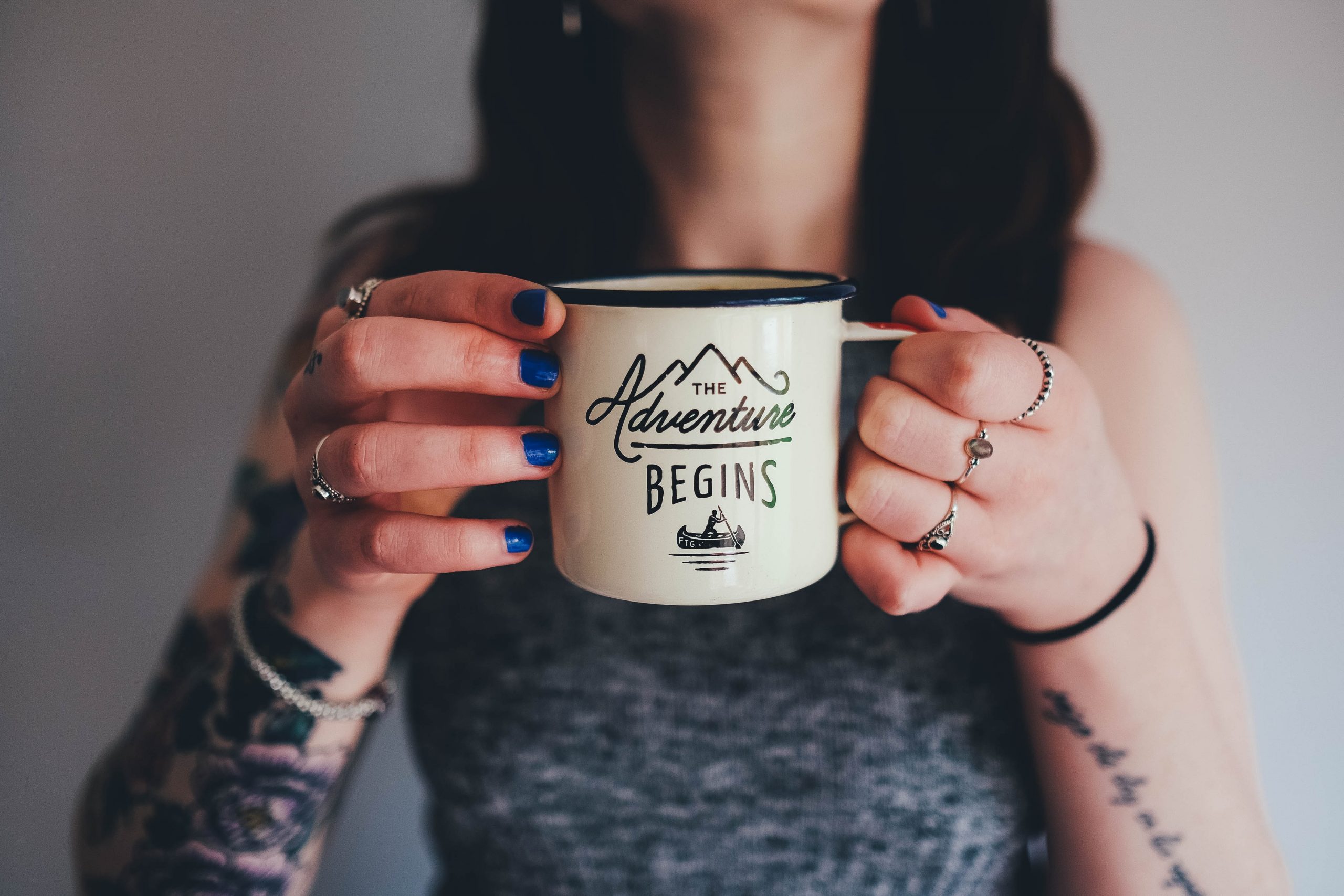 A woman holding a customized mug that reads ‘the adventure begins’