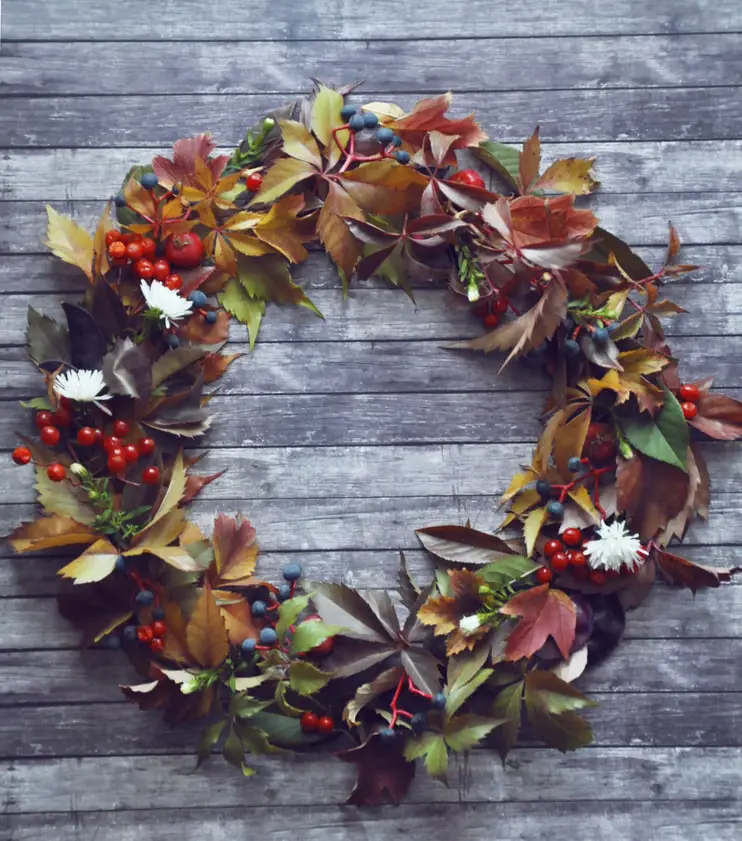 A wreath made with fall leaves and berries of different colors