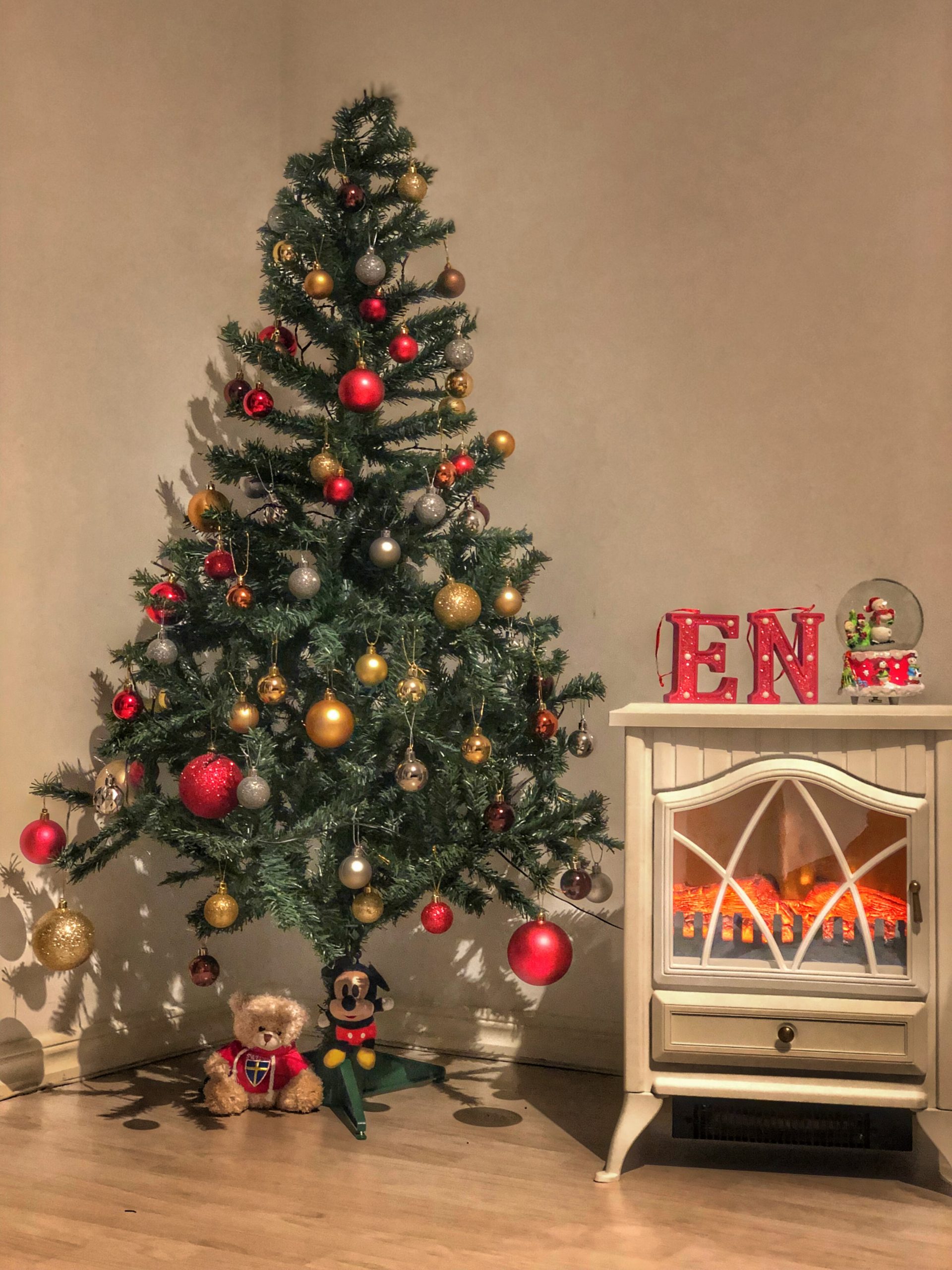 A Christmas tree decked with ornaments placed beside a table.