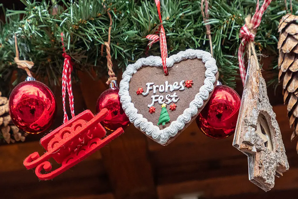 decorative elements hanging from a christmas tree Red decorative balls, a red sleigh, a brown heart, and a wooden imitation of a Christmas tree.