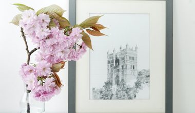 Flowers placed inside water in a glass bottle and a black and white photo of a monument in the background.