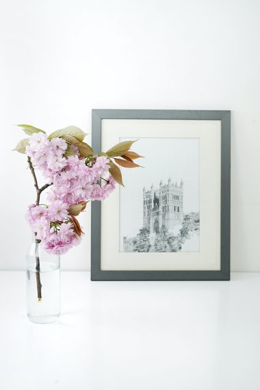 Flowers placed inside water in a glass bottle and a black and white photo of a monument in the background.