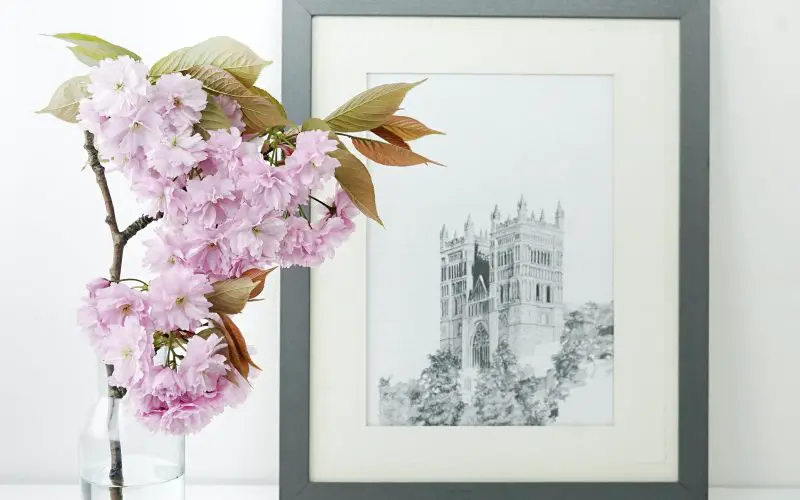 Flowers placed inside water in a glass bottle and a black and white photo of a monument in the background.