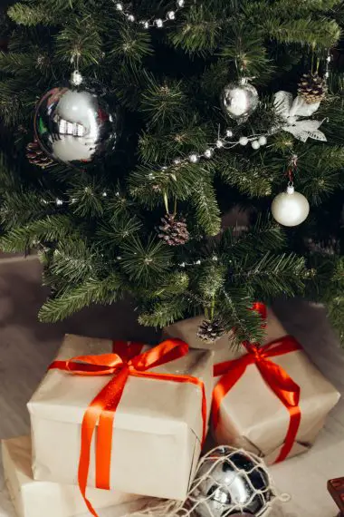 A Christmas wallpaper iPhone of two gift boxes under a Christmas tree