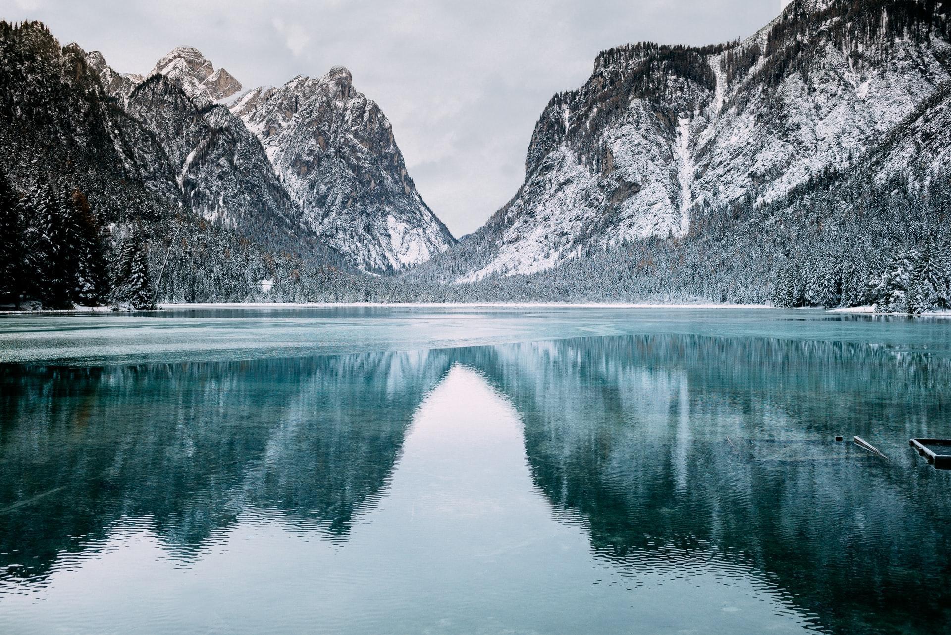 A lake surrounded by mountains covered in patches of snow