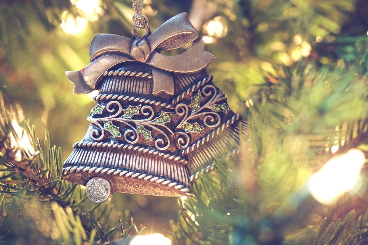 Two silver Christmas bell ornaments on a tree