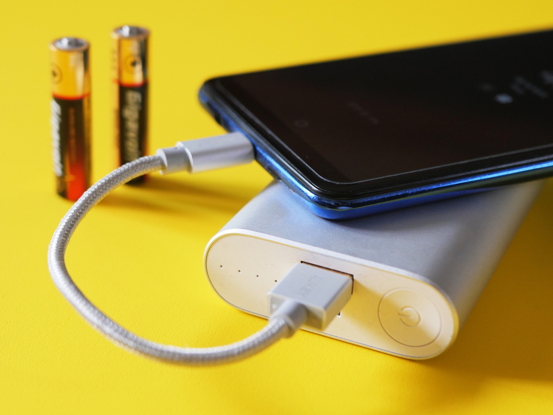 A smartphone getting charged from a white power bank.