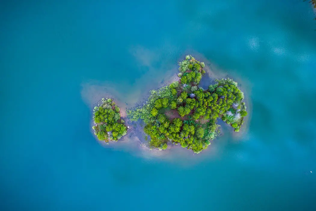 A hilly island filled with greenery surrounded by calm waters of the ocean